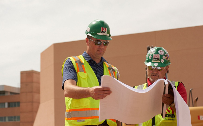Two Jaynes employees working on a hospital expansion project. One is on his knees fitting a concrete frame in place.