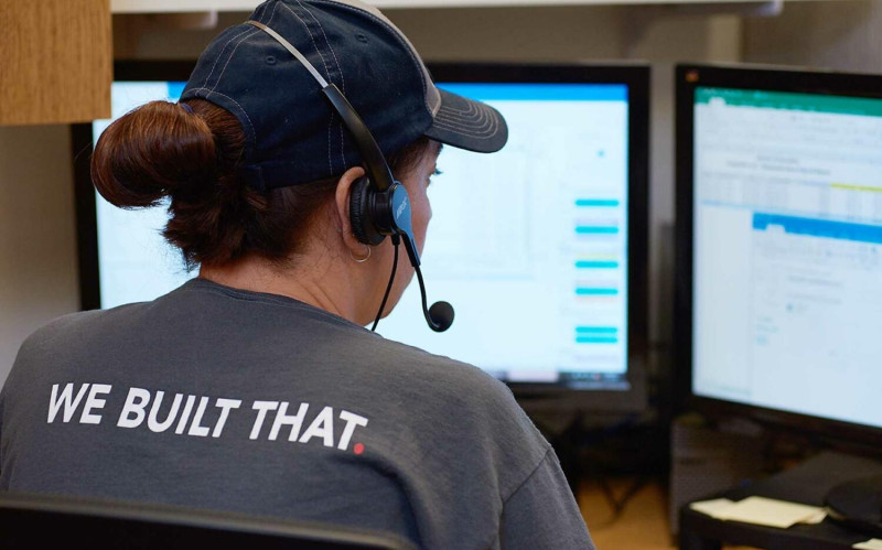 A female project manager examining workflows on a screen. Her shirt reads 'We Built That.'